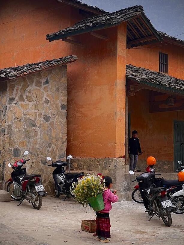 Ragazza Hmong che vende fiori selvatici in un villaggio di Ha Giang